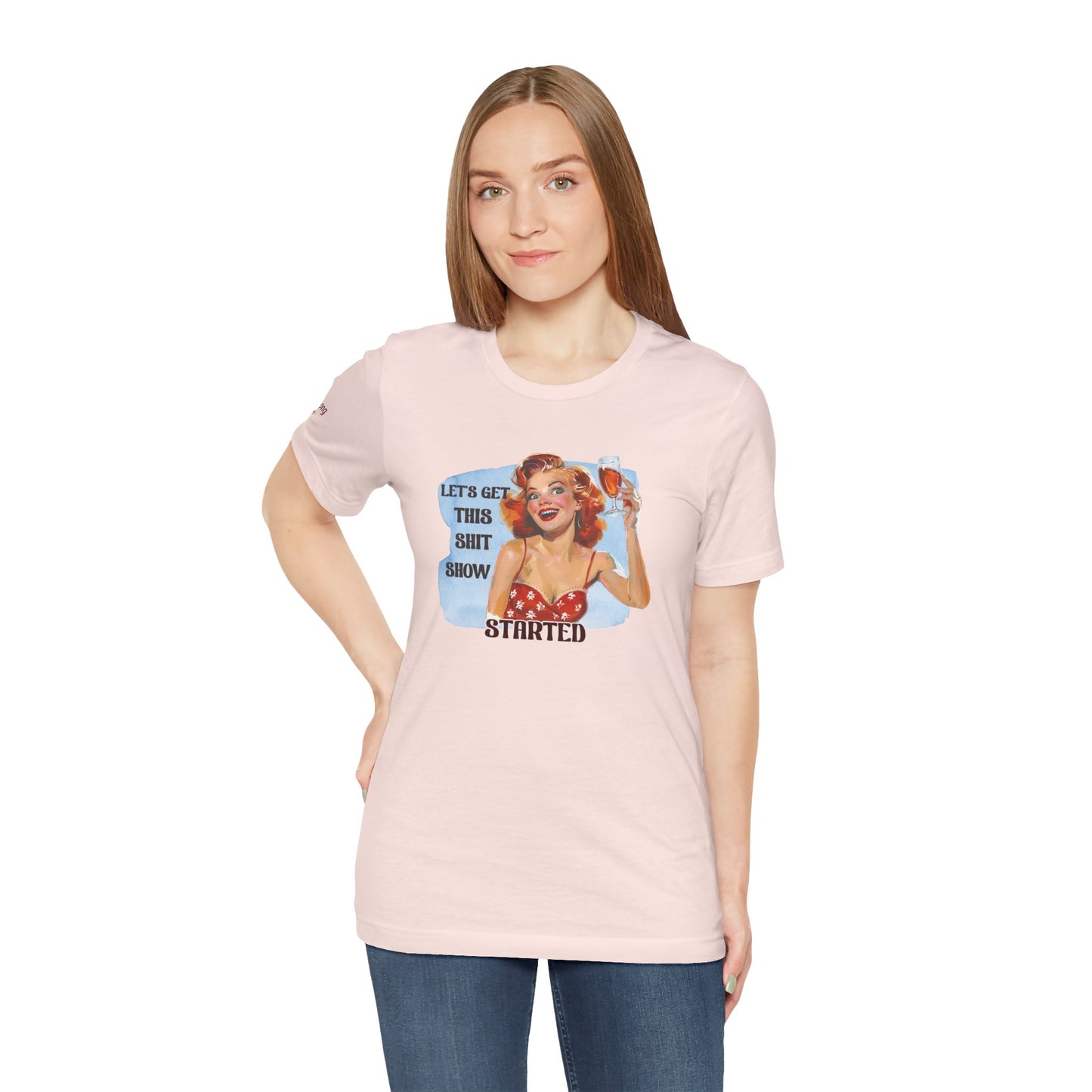 Vintage pin-up woman with bright red hair, holding a glass of wine with a manic smile. The phrase reads: "Let’s Get This Sh*t Show Started."