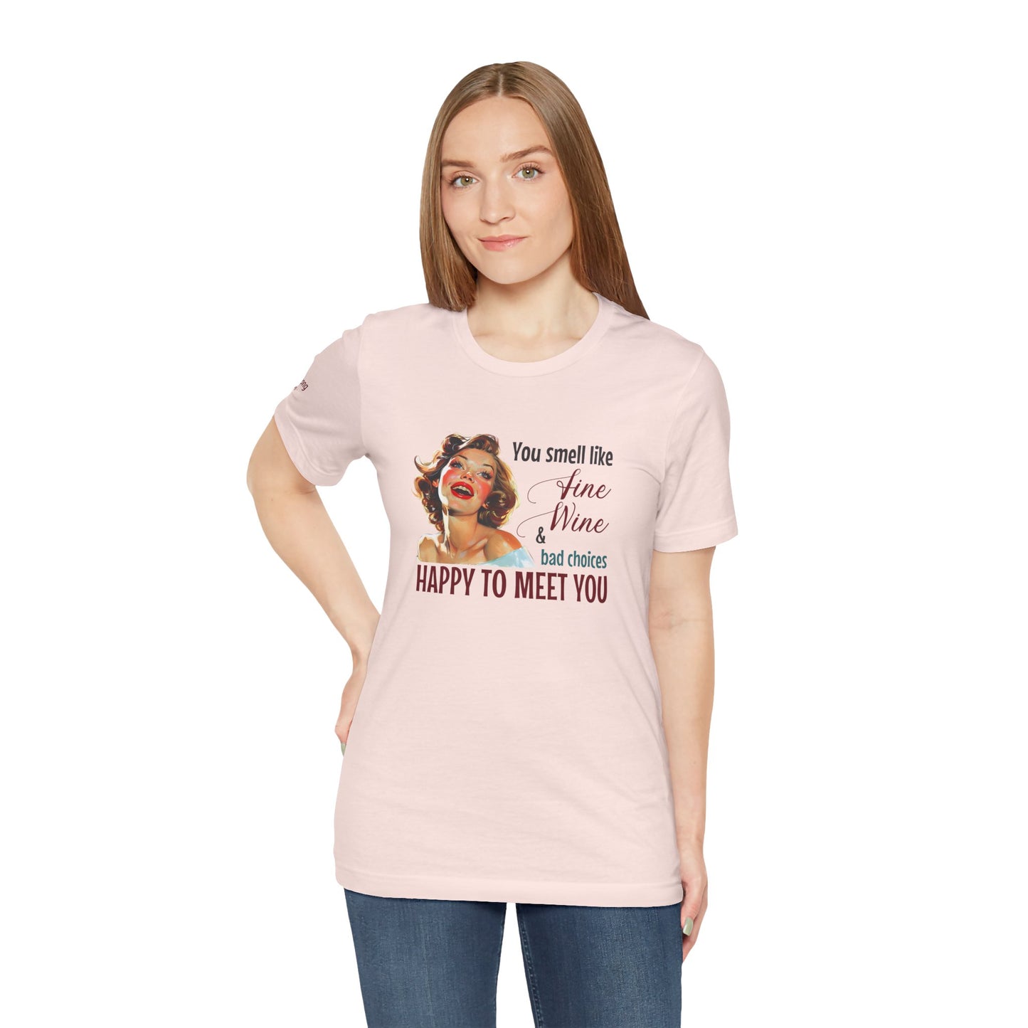 A cheerful, rosy-cheeked pin-up girl with wavy blonde hair smiles brightly. The design features playful retro lettering with the phrase "You smell like fine wine & bad choices – happy to meet you!" in bold, vintage script.