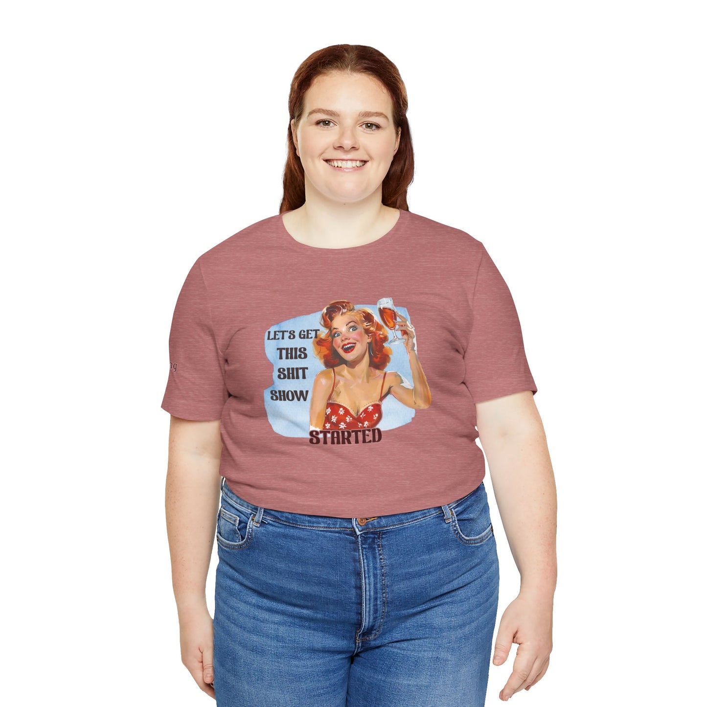 Vintage pin-up woman with bright red hair, holding a glass of wine with a manic smile. The phrase reads: "Let’s Get This Sh*t Show Started." - in plus sizes.
