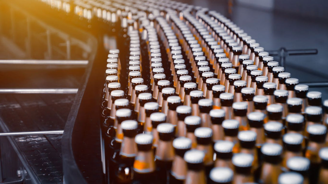 A long assembly line of beer bottles moving through a brewery, representing the complexity of beer production and distribution—if only shipping it were this easy!