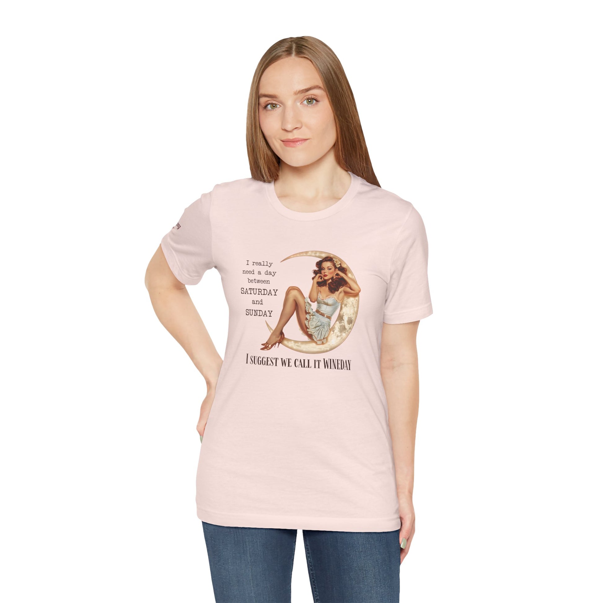 A glamorous pin-up girl in a vintage ruffled dress sits on a glowing crescent moon, touching her hair with a dreamy expression. The text reads: "I really need a day between Saturday and Sunday. I suggest we call it WINEDAY" in bold vintage-style font.