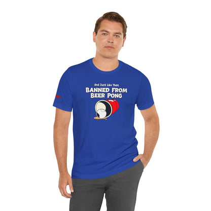 Funny beer pong t-shirt featuring a spilled red party cup and beer pong ball. The text reads “And Just Like That, Banned from Beer Pong” in a bold, playful font.