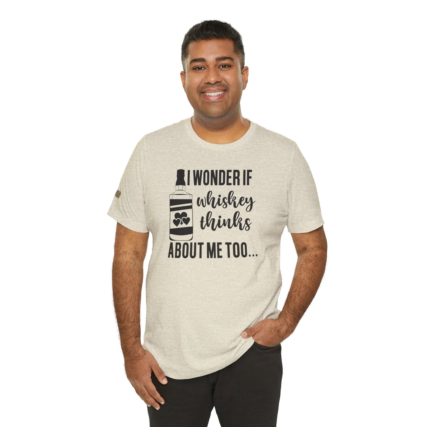 Funny whiskey drinking t-shirt featuring bottle graphic and humorous text "I Wonder If Whiskey Thinks About Me Too". Shown in shade of beige; available in may colors and plus sizes.