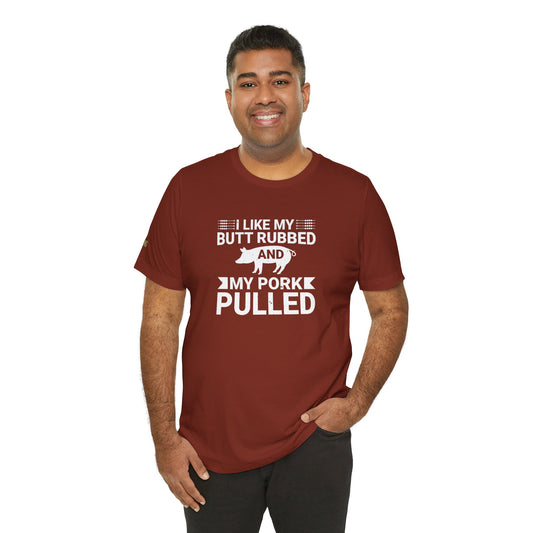 BBQ-themed t-shirt design with the phrase "I Like My Butt Rubbed & My Pork Pulled" featuring a pig silhouette and grilling utensils.