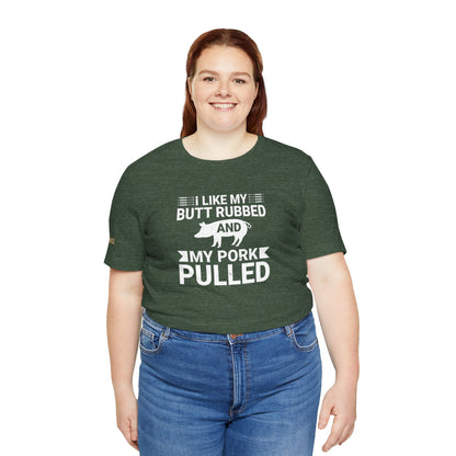 BBQ-themed t-shirt design with the phrase "I Like My Butt Rubbed & My Pork Pulled" featuring a pig silhouette and grilling utensils. Available in plus sizes.
