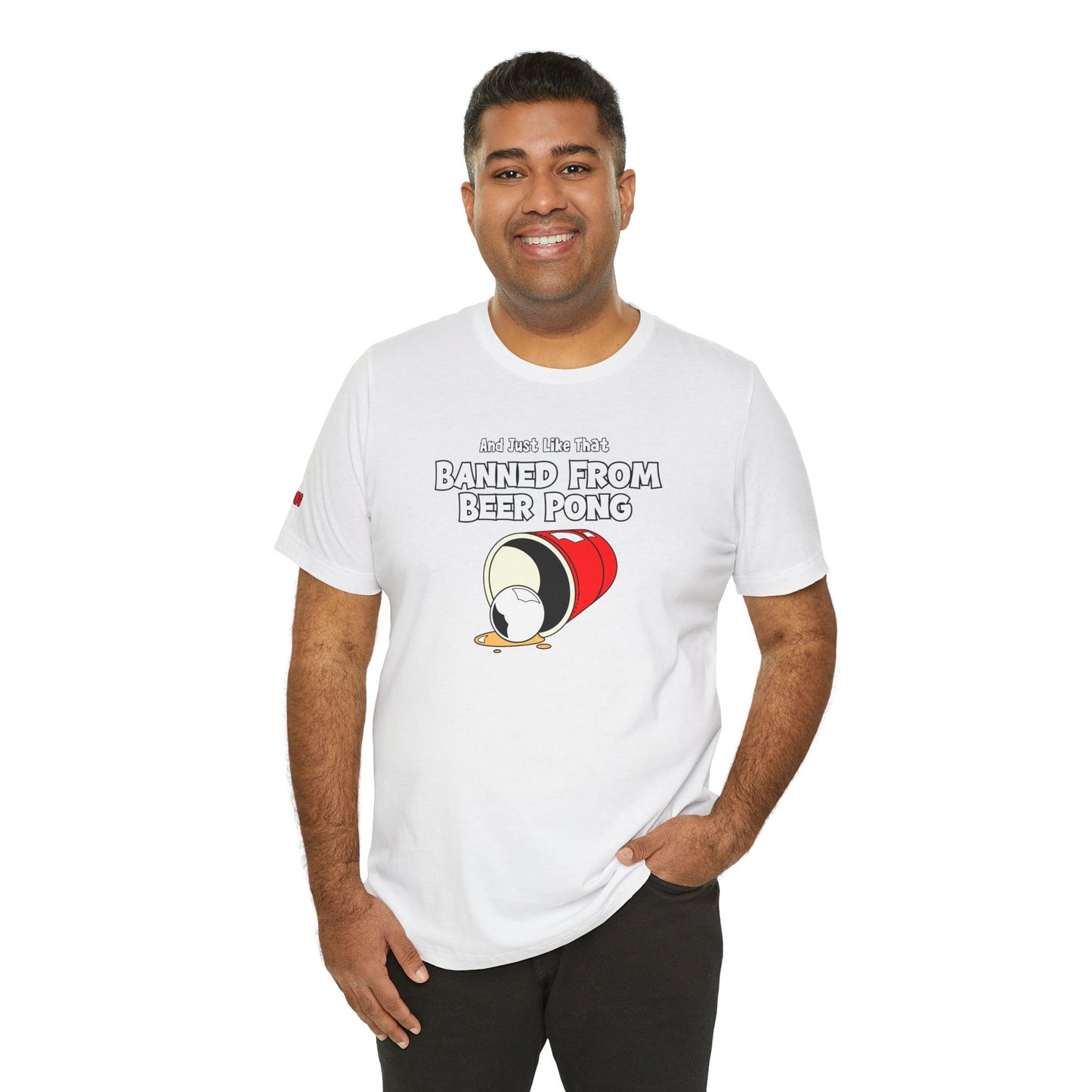 Funny beer pong t-shirt featuring a spilled red party cup and beer pong ball. The text reads “And Just Like That, Banned from Beer Pong” in a bold, playful font.