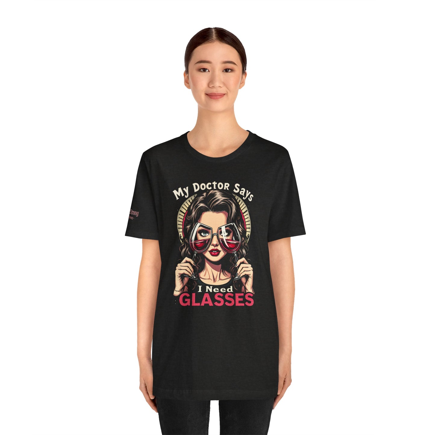 Illustration of a stylish woman holding two red wine glasses as eyeglasses, with bold text reading “My Doctor Says I Need Glasses.” A perfect funny wine t-shirt for moms, wine lovers, and brunch enthusiasts.