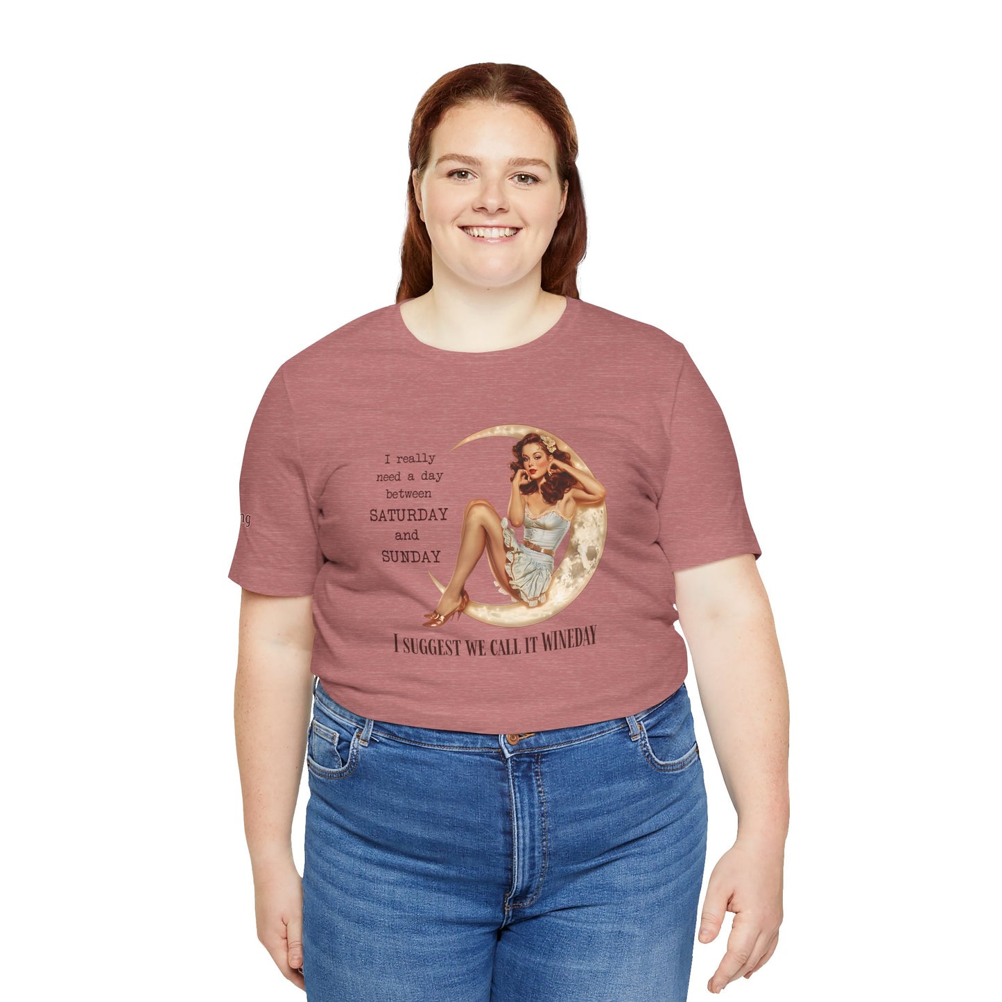 A glamorous pin-up girl in a vintage ruffled dress sits on a glowing crescent moon, touching her hair with a dreamy expression. The text reads: "I really need a day between Saturday and Sunday. I suggest we call it WINEDAY" in bold vintage-style font. Available in plus sizes.