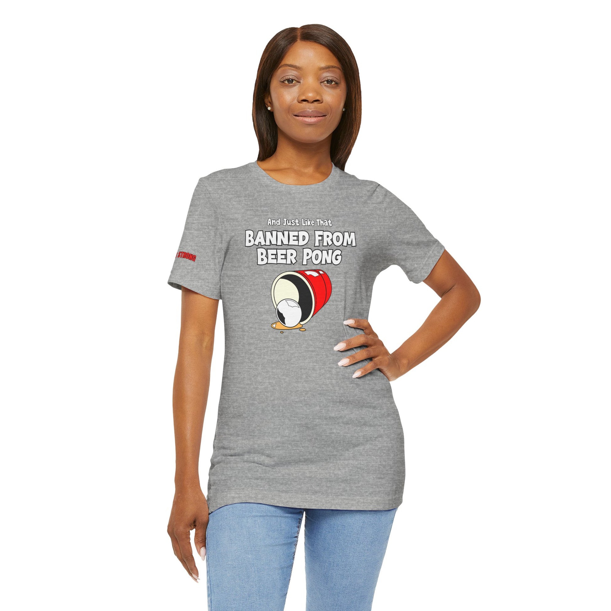 Funny beer pong t-shirt featuring a spilled red party cup and beer pong ball. The text reads “And Just Like That, Banned from Beer Pong” in a bold, playful font.