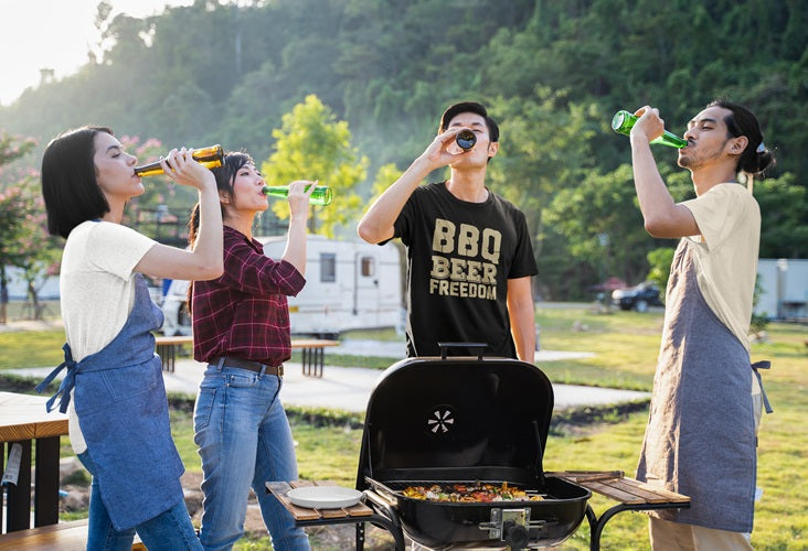 Four individuals standing around BBQ drinking beer. One wearing a Beer Strong tee with quote "BBQ, BEER, FREEDOM" from the BBQ and Beer Collection.