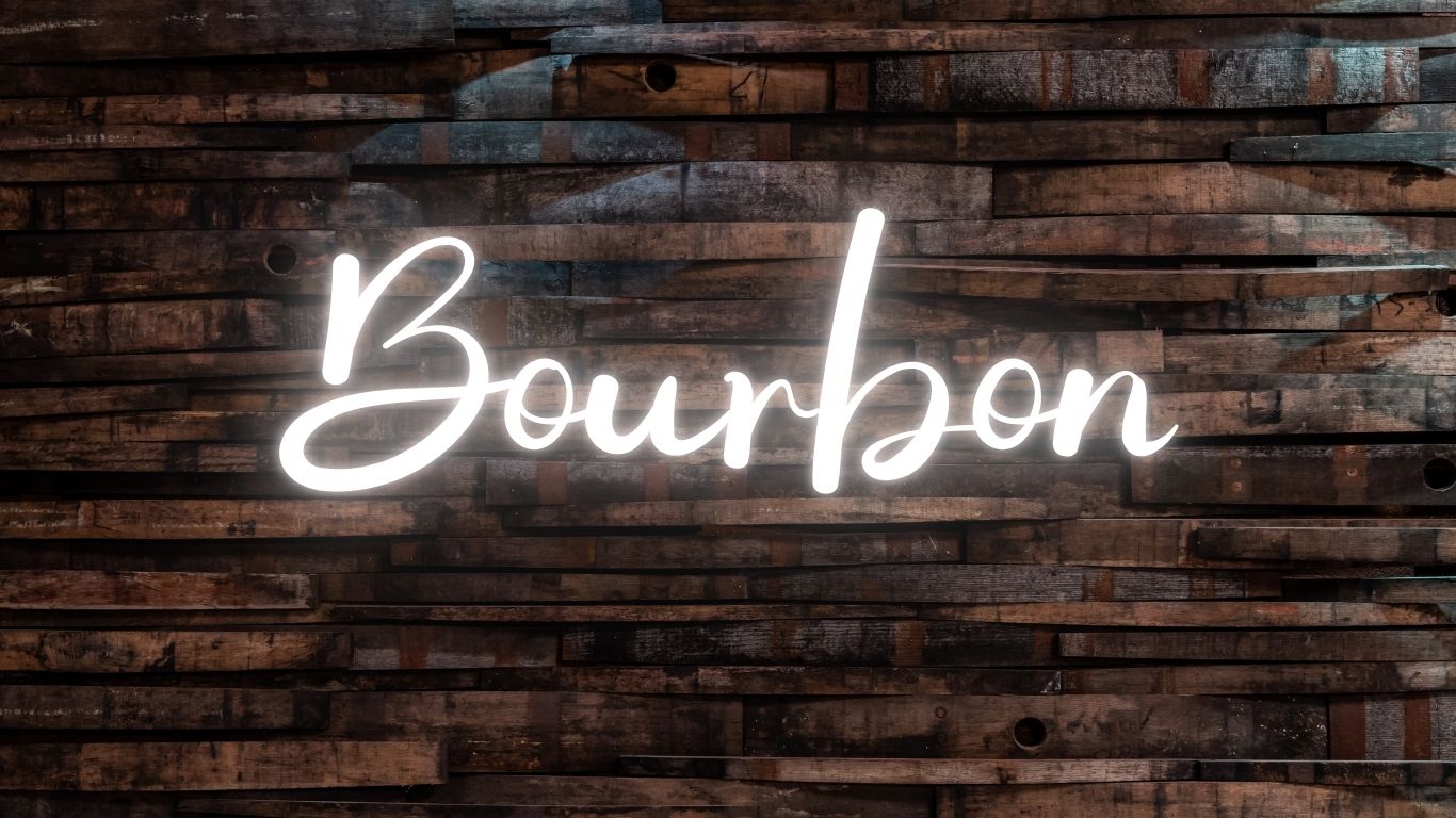 Bourbon neon sign glowing against a rustic whiskey barrel wood background – a bold and classic design for bourbon lovers, whiskey fans, and alcohol-themed t-shirts & gifts from Beer Strong.