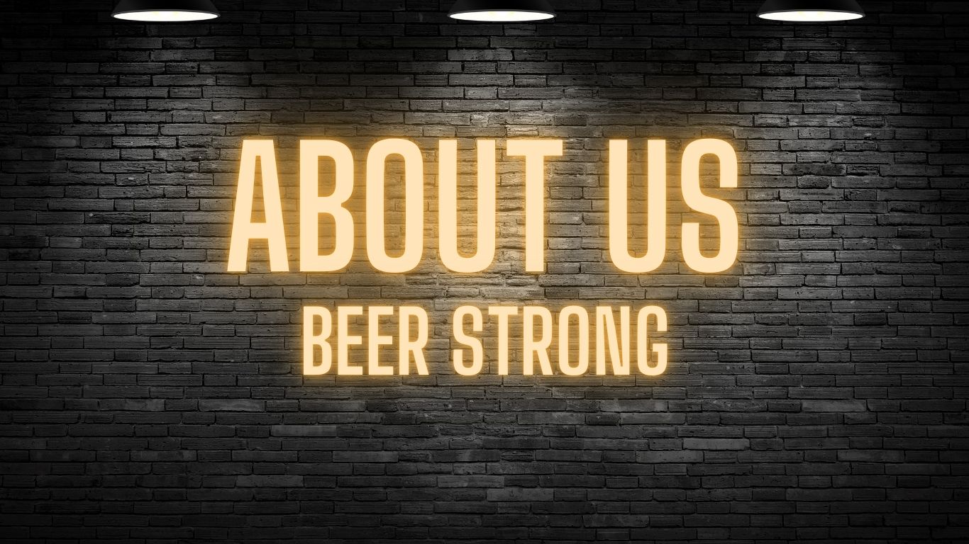 Neon glow of "About Us - Beer Strong" against dark brick wall. A brand dedicated to funny alcohol quotes on t-shirts, hoodies, hats and accessories.